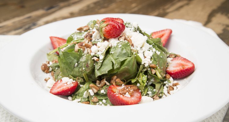 A plate of spinach salad topped with juicy strawberries and crunchy nuts.