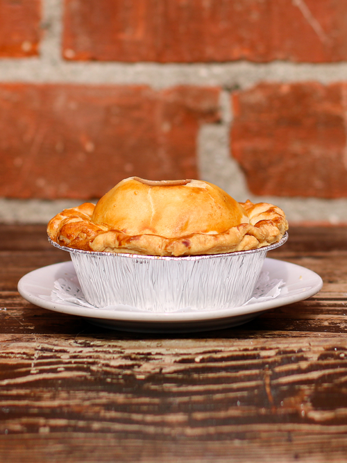 A savory mini Thanksgiving pie showcased on a plate, gracefully situated on a wooden table. .